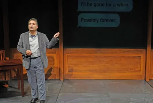 A man gives a presentation on stage with a dark background.
