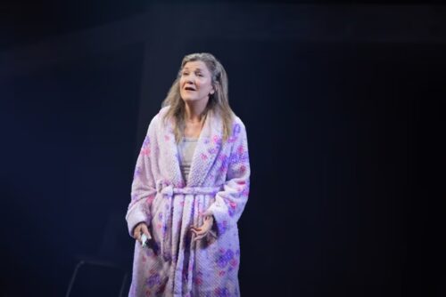 Woman in a floral robe singing on stage.