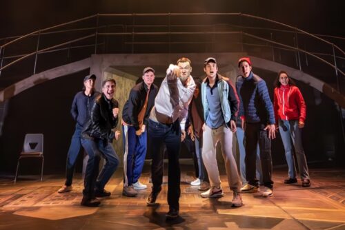 A diverse group of young men posing confidently on a stage.