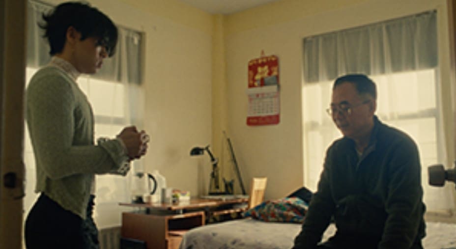 Two people exchanging or handing over an object in a dimly lit room.