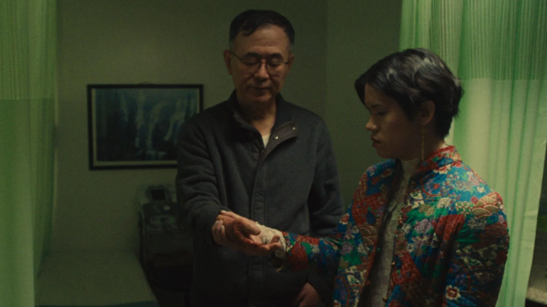 Two people exchanging or handing over an object in a dimly lit room.