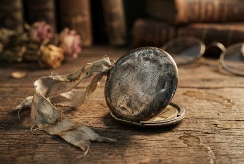 antique-pocket-watch-with-worn-ribbon-on-wooden-table.