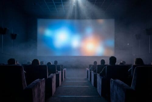 An audience watching a film in a dimly lit theater.