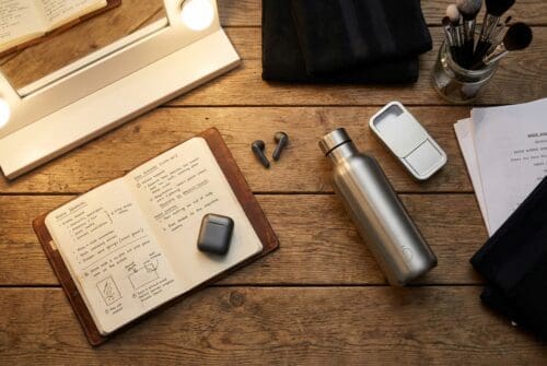 desk with journal, earbuds, water bottle, and grooming items.