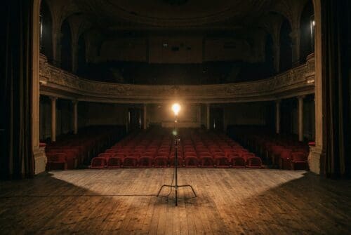 dim-theater-stage-with-lit-bulb,-empty-red-seats