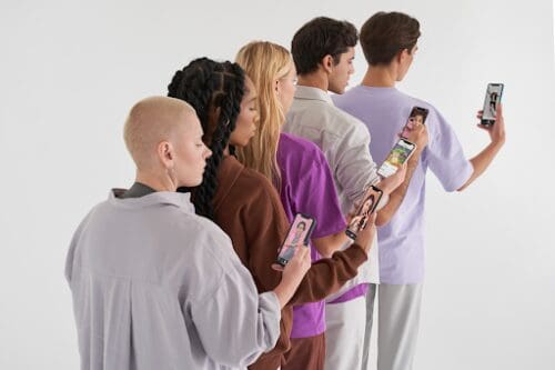 Five people of varying backgrounds looking at mobile phones.
